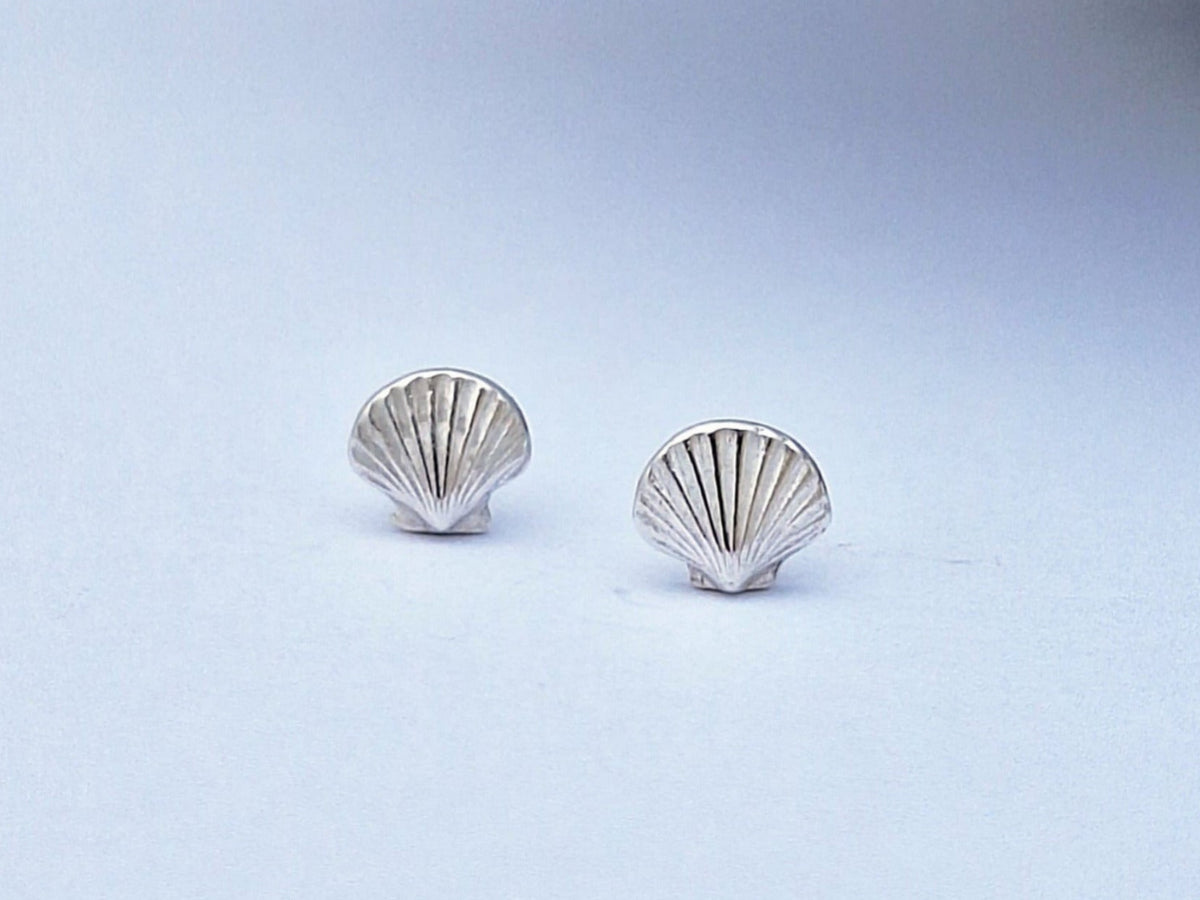 A pair of sterling silver stud earrings in the shape of clam shells, displayed against a light background.